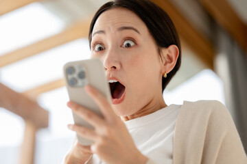 スマホを見ながら驚く女性