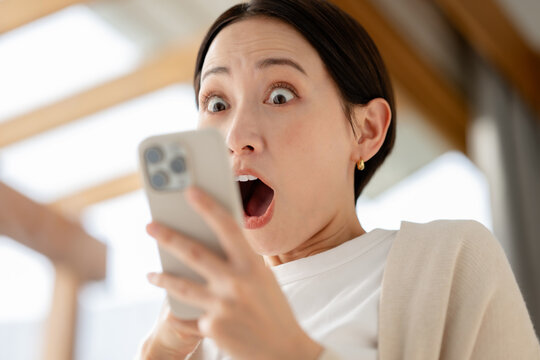 スマホを見ながら驚く女性