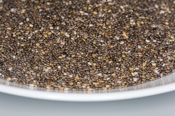 Raw chia seeds on a dish, front view close-up
