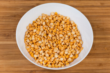 Yellow split peas in bowl on a wooden bamboo surface