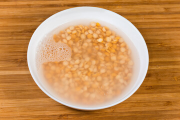 Yellow split peas soaked in cold water in white bowl