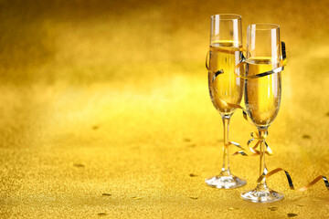 Champagne in glasses, confetti and streamers on golden background. Space for text