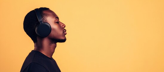 Young man with headphones in a warm-toned studio setting showcasing concentration and creative energy with ample copy space for text