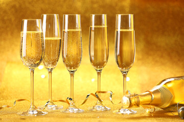 Champagne in glasses, bottle and streamers on golden background