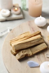 Palo santo sticks, gemstones and burning candles on light table, closeup