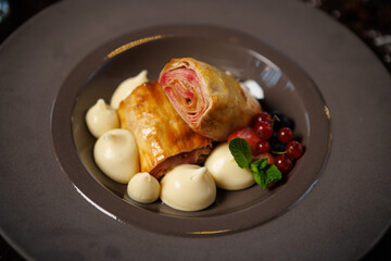 Puff pastry dessert with berry filling. Served with vanilla cream dollops, fresh red currants, blueberries, and mint leaves. Delicious gourmet dessert closeup in modern cuisine restaurant