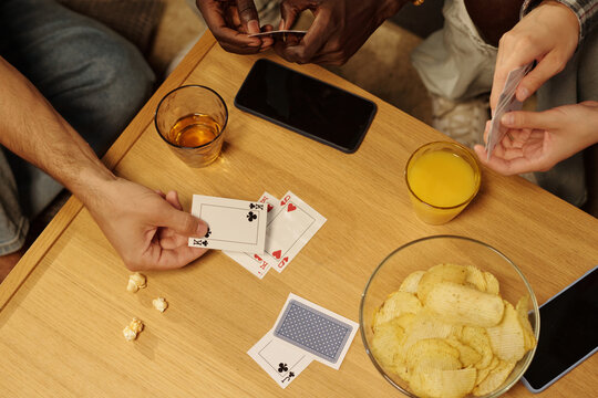 High angle of hand of guy putting clubs king playing card on hearts queen during tabletop game