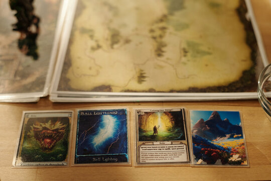 Row of four cards with magic illustrations, maps or pictures for board game lying on wooden table