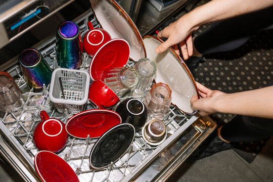 Specialty coffee cups and saucers being loaded into dishwasher