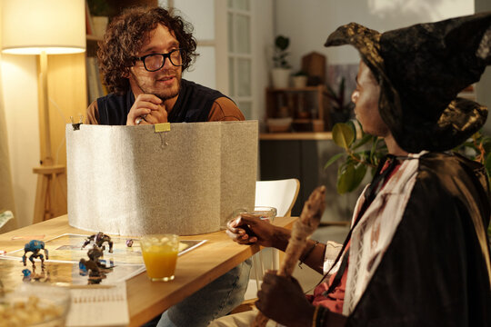 Young man guiding tabletop game looking at African American male participant during interaction