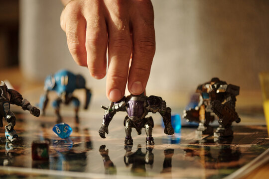 Hand of young man putting toy warrior on board game picture with dice cubes or moving it along table