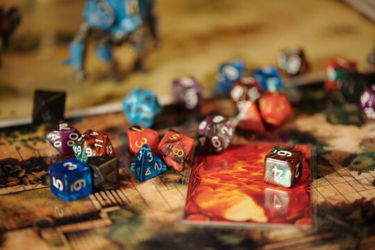 Focus on several dices with numbers on card and pictures of board game about magic and adventures