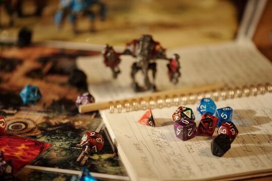 Focus on page of copybook with written instructions and rules of board game lying on pictures or maps