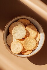 top-down view of rice crackers in various flavors including soy and sesame served in ceramic bowl illuminated by soft