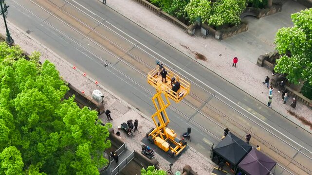 Aerial - film crew stand on electric scissor lift during movie production