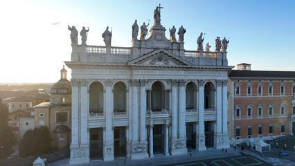 Obraz premium Controluce sulla basilica di San Giovanni in Laterano a Roma Vista aerea della facciata e delle statue sul tetto della basilica