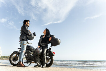 Obraz premium Bikers couple talking on the beach with their motorcycle