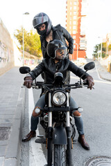Fototapeta premium Bikers couple wearing protective helmets riding motorcycle in city street