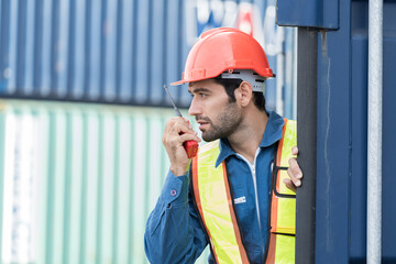 Male worker working at container cargo site control loading containers boxes and checking up goods...