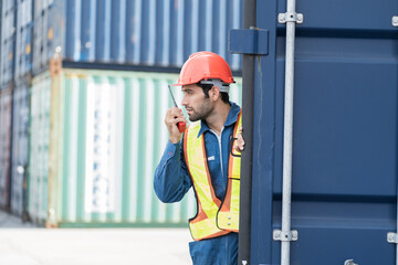 Male worker working at container cargo site control loading containers boxes and checking up goods...