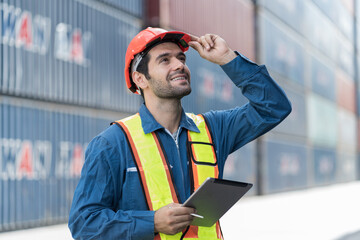 Male worker working with digital tablet at container cargo site control loading containers boxes...