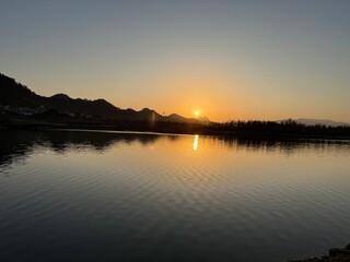 Golden Sunset Over a Serene River with Distant Mountains