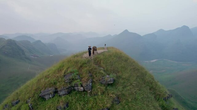 Scenery of Ba Guang grass hill, Mountain range with fog and villager bringing horse to graze on the mountain in the morning