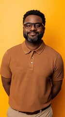 Obraz premium Smiling man in brown polo shirt stands against a vibrant yellow background showcasing a confident pose and warm demeanor