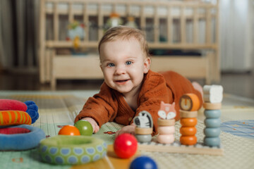 A six-month-old baby plays on the floor with colorful toys. The baby learns to crawl. Portrait of a...