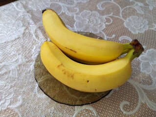 Yellow delicious healthy bananas on a plate on the kitchen table. Food and fruit theme.