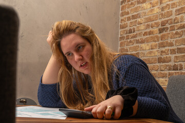 Confused Woman completing US 1040 income tax form while analyzing finances at a workspace