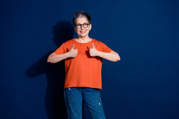Photo portrait of attractive senior woman show thumb up dressed stylish orange clothes isolated on...