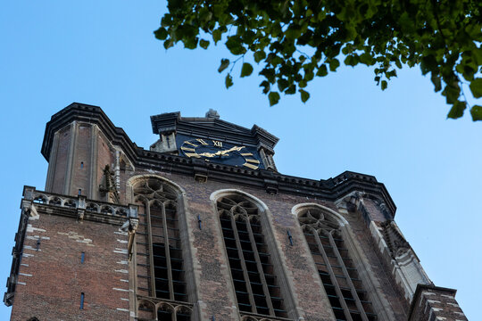 A majestic Gothic church under a dramatic cloudy sky. The intricate brickwork, towering windows, and clock tower reflect its historic architecture and timeless grandeur.