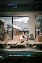 Woman in a white robe enjoys a cocktail while relaxing in a serene spa setting with mountain views