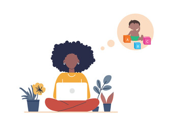 A young African American woman working on a laptop while thinking about her child. She is sitting cross-legged in a cozy home setting, surrounded by plants.