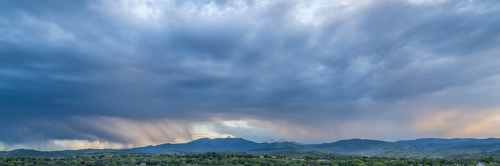 Obraz premium dramatic storm clouds at dusk over Rocky Mountains and lake in northern Colorado