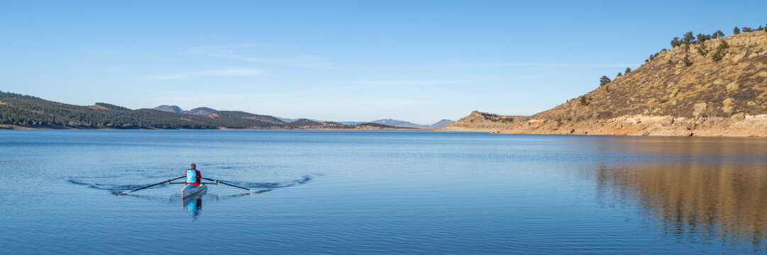 Lonely rower in a coastal rowing shell - Carter Lake in fall or winter scenery in northern Colorado. - Powered by Adobe
