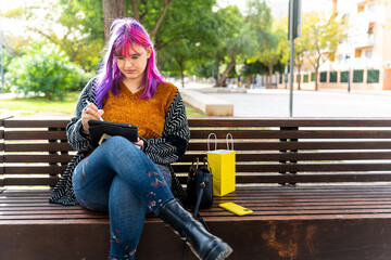 Body positive autistic woman using digital tablet on park bench