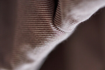 Close up detail of beige textured fabric with visible ribbed pattern and soft wrinkles.