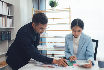 Strategic Collaboration: A focused business meeting in a professional setting.  A male and female professional work together, leaning in and collaborating on a project.