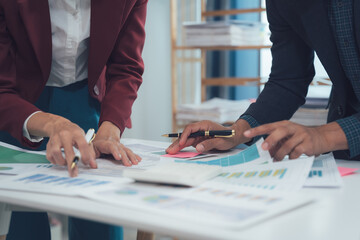 Strategic Collaboration: Two business professionals meticulously review financial charts and...