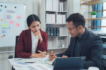 Business Collaboration: A focused business meeting with two colleagues, one male and one female, ...