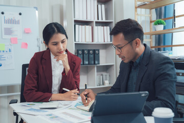 Strategic Collaboration: Focused business colleagues engrossed in a serious discussion, reviewing documents and utilizing a tablet in a modern office setting.  
