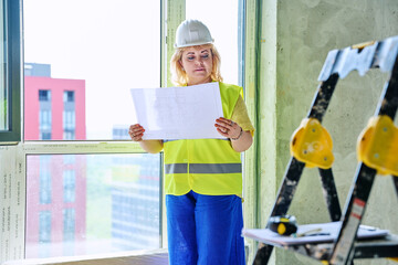Technical profession woman in protective vest helmet working on construction