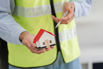 Construction professional holding a scale model of a house during a project discussion