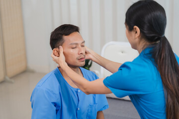 Compassionate Care: A close-up of a female healthcare professional gently touching the forehead of...