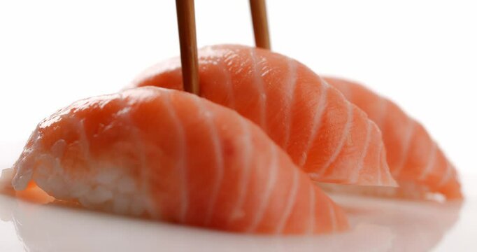 one piece of Japanese nigiri salmon sushi being put on the table in the middle for serving the meal in front of white background