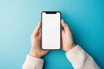 Woman hand holding smartphone mobile phone with white blank empty screen mockup template against pastel blue background. Commercial business and online shopping retail concept.