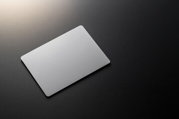 modern blank credit card photographed against matte black surface accented by soft spotlight