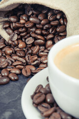 Coffee in white cup and roasted dark coffee beans in bag